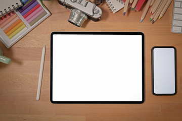 Blank screen tablet on wood stylish desk with creative photographer supplies and copy space