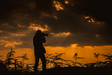 A photographer standing on top of Mountain at sunset