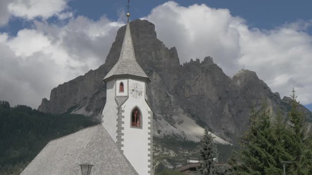 Panning shot of village church in Corvara and surrounding mountain peaks, Alta Badia, Province of Belluno, Italian Dolomites, Italy, Europe