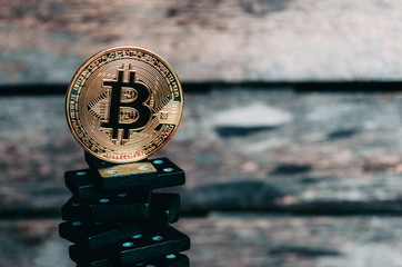 Bitcoin coin on top of a pyramid of dominoes.