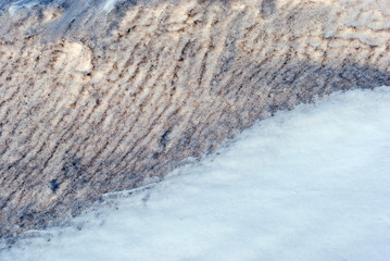 Melting snow, yellow wet lines texture, early spring, natural background, close up detail