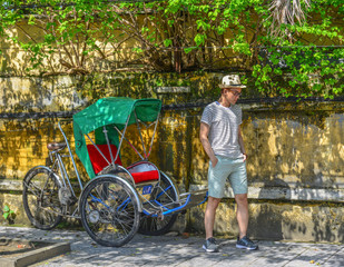 A young man standing near cycle at old town