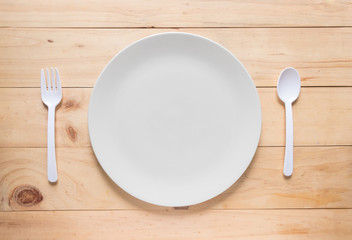 Empty white round dish or plate on wooden background, top view of tableware with copy space
