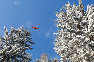 Czerwony helikopter na tle niebieskiego zimowego nieba