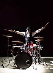 Professional drummer playing on drum set on stage on the black background