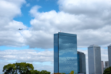 Skyscraper reflection cloud in downtown and airplane flying on blue sky