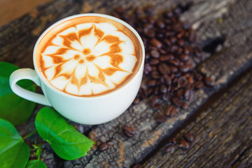 hot cappuccino on wood table /hot cappuccino with coffee bean and green leaf on wood table