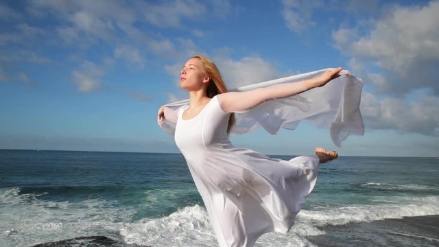 Freedom Concept . Women in white dress and with scarf standing on the Rock. Dancing. Flying. Moving. Doing gymnastic elements.