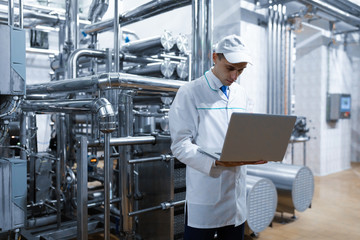 Technologist with a laptop in his hands at the dairy plant