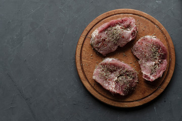 Three raw stakes with rosemary on round board