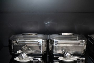 Black and white image of metal containers and tongs on the plate