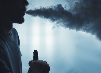 A bearded man in the clouds of steam from electronic cigarette closeup. vaping man