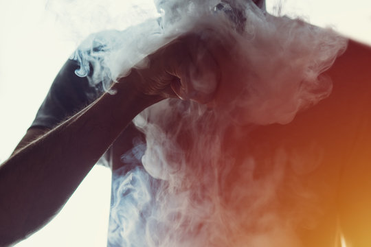 Vaping man. Close-up of a man with a beard releases a cloud of steam