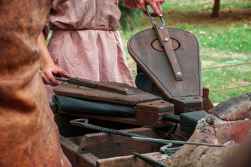 Medieval blacksmith using pair of bellows to light fire in furnace in smithy. Reconstruction