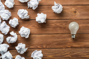 Ideological concept with wastepaper light bulb on wooden table