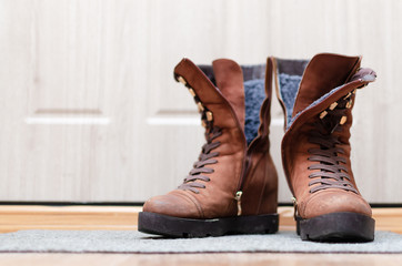 Female suede brown boots on the floor in a hallway.