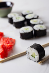 roll with cucumber, ginger and soy sauce close-up on a white background.