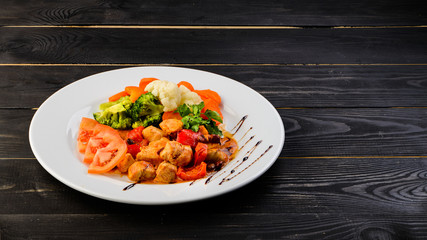 italian dish of chicken and vegetables on wooden black background