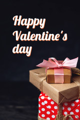 Holiday boxes Packed in crafting paper on dark wooden background. Vertical card Happy Valentine's day with text