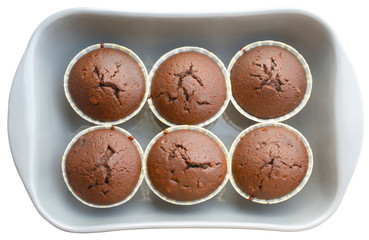 Homemade chocolate cupcakes in ceramic baking tray. Each muffin in a separate paper baking dish. Isolated on white.