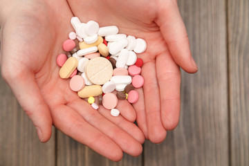 pills in a hand on a wooden background