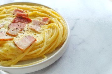 Close up of spaghetti carbonara on white plate.