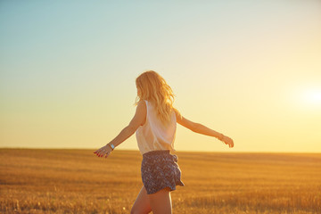 Cute young woman jumping in a wheat field.