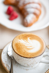 Coffee cappuccino with croissant on white plate in restaurant. Light morning Breakfast, fresh warm...