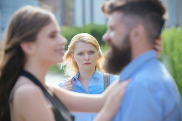 A jealous girlfriend. Unhappy girl feeling jealous. Bearded man cheating his girlfriend with another woman. Romantic couple of man and woman dating. Jealous woman look at couple in love on street - obrazy, fototapety, plakaty