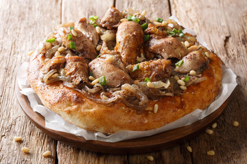 Middle Eastern meal of chicken with sumac, pine nuts and onions on a flat bread closeup. horizontal