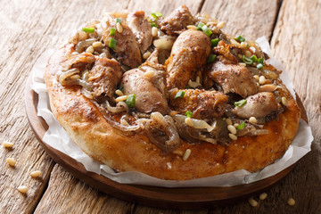 Palestinian dish of chicken with sumac, pine nuts and onions on a flat bread closeup. horizontal