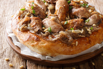 musakhan chicken with sumac, pine nuts and onions on a flat bread closeup. Horizontal