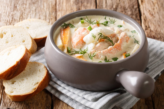 Rustic style portion of fish soup with cream, carrots and celery close-up in a bowl and bread. horizontal