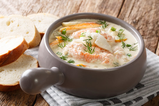Closeup of creamy fish soup with cod, salmon, carrot and celery in a bowl served with fresh bread. horizontal