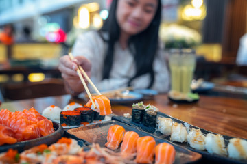 Asian lady eat a Salmon fish sashimi and Sushi in Japanese restaurant
