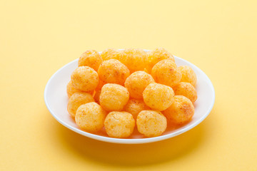 Cheese ball in a ceramic dish on yellow background.