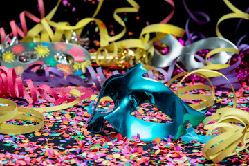 blue carnival mask over confetti and multi-colored streamers
