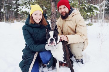 Happy couple in love having fun in the snow with his baby dog