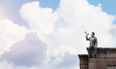 Businessman or manager on building roof announcing something in loudspeaker
