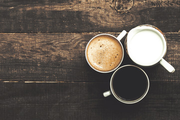 A cup of black coffee and coffee with cream on a wooden background. Top view