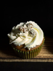 lighted cupcakes on a wooden board against a black background
