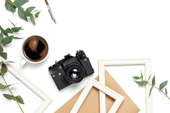 Photo frame old retro camera notebook diary cup of coffee pens eucalyptus leaves on white background. Flat lay top view copy space. Stylish minimal composition artwork mockup Feminine desk workspace