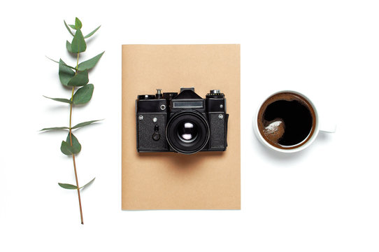 Old retro camera notebook diary cup of coffee eucalyptus leaves on white background. Flat lay top view copy space. Stylish minimal composition artwork mockup Feminine desk workspace