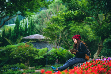 woman travel nature in the flower garden. relax sitting on rocks and reading books In the midst of nature at national park doi Inthanon...