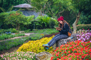 woman travel nature in the flower garden. relax sitting on rocks and reading books In the midst of nature at national park doi Inthanon...