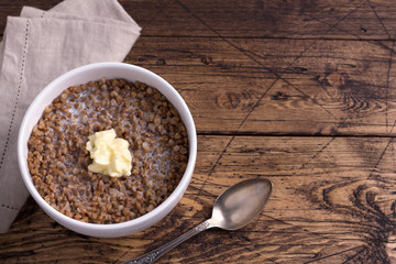 Homemade delicious healthy breakfast. Buckwheat porridge with milk and butter on a wooden table, horizontal, free space