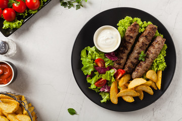 Traditional cevapcici served with baked potatoes. Flat lay. Stone background.