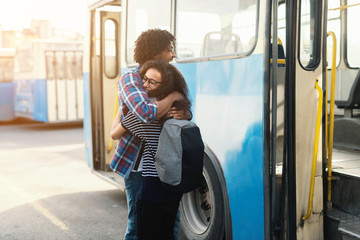 Happy couple hugging in front of bus. Public transportation concept.