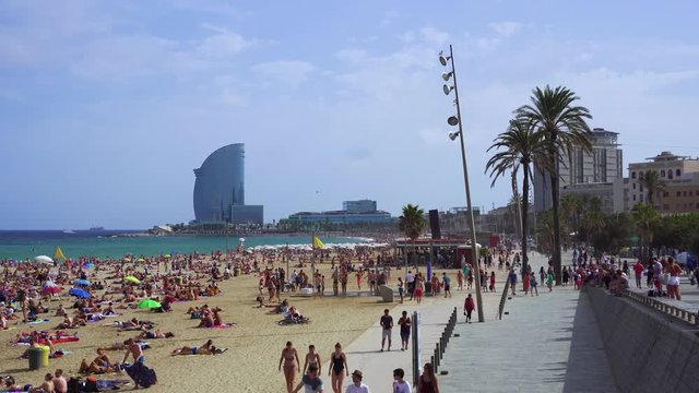 Bathers on a crowded sandy beach with background view of W sail shaped hotel, Barcelona Beach, Catalonia, Spain, Europe