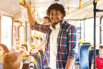 Young smiling African American man riding in the city bus and looking at camera.